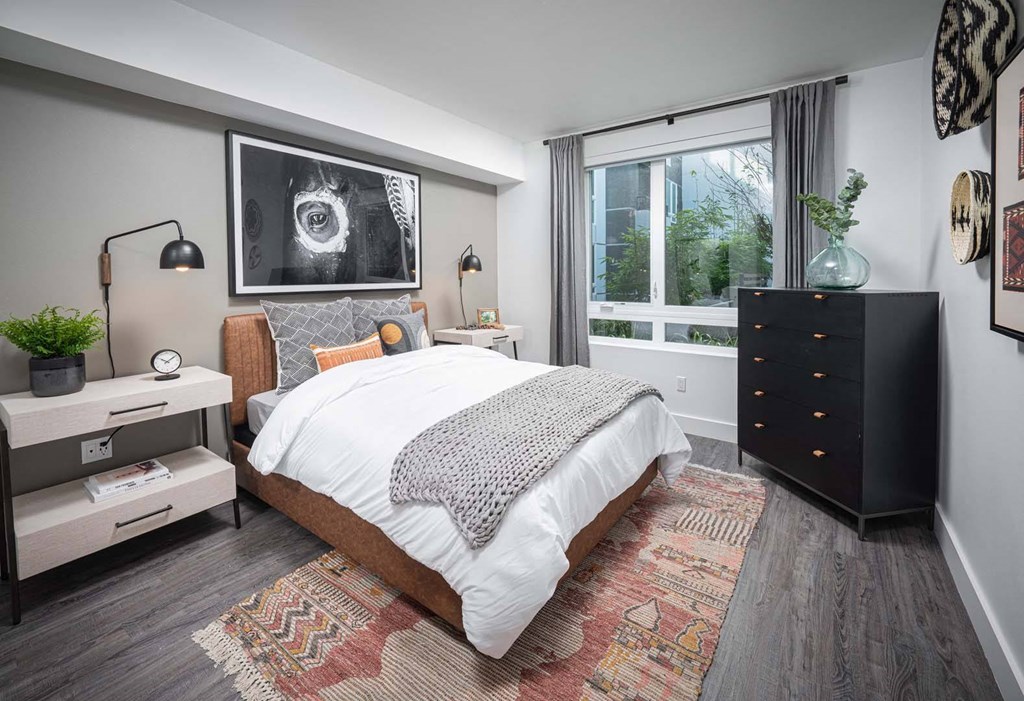 a bedroom with a bed and a dresser in front of a window