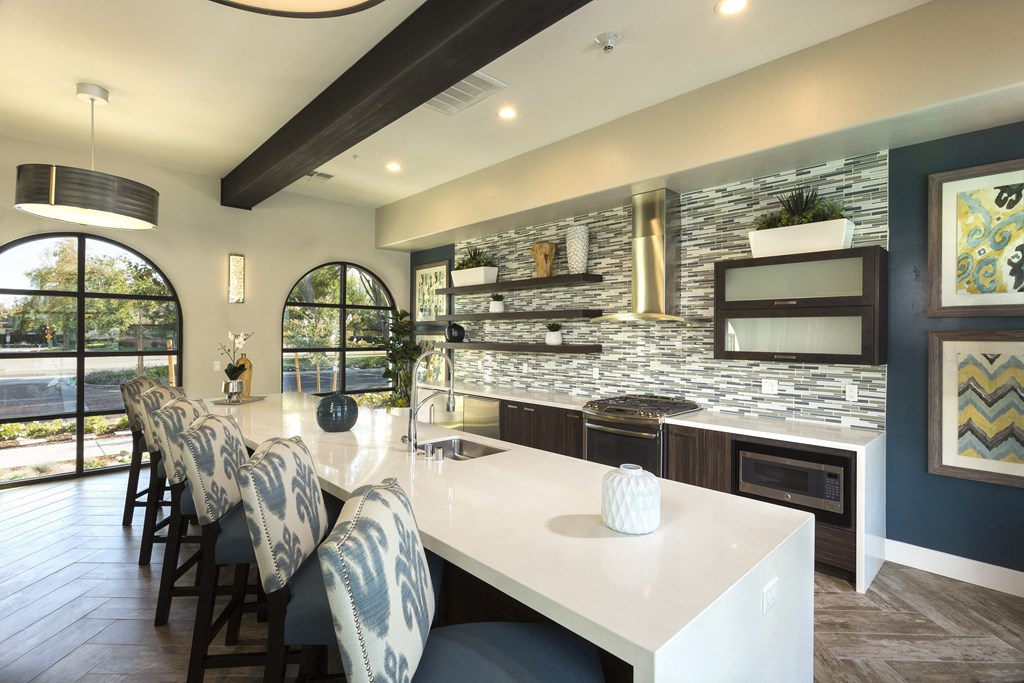 a kitchen with a long island with a white countertop and a long white table with blue