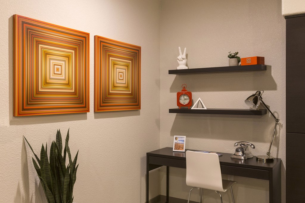 an office with a desk and chair and two paintings on the wall