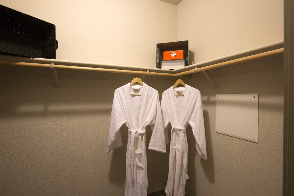 a walk in closet with two white robes hanging on the wall