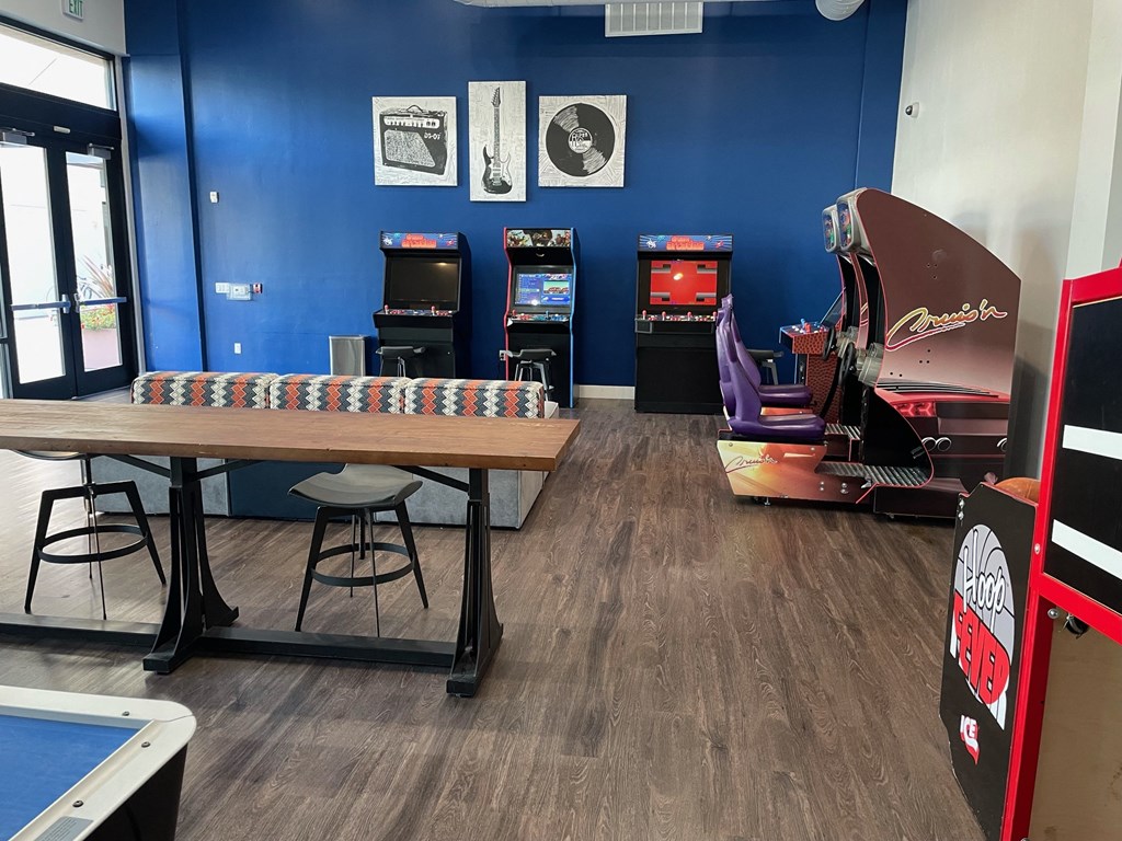 a recreation room with a table and arcade games