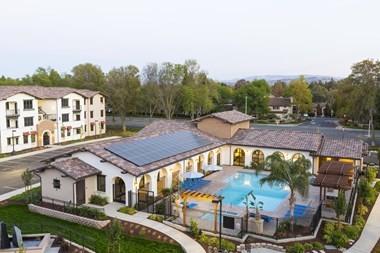 an aerial view of a resort style pool with palm trees and a parking lot in the background
