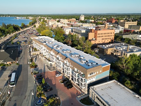 A large building with a blue roof is in the center of a city street.