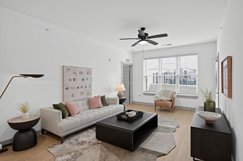 A modern living room with a grey sofa, a black coffee table, and a ceiling fan.