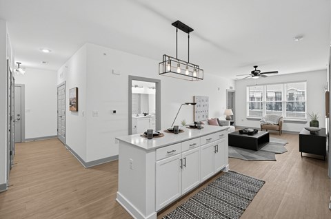 A modern kitchen with white cabinets and a wooden floor.