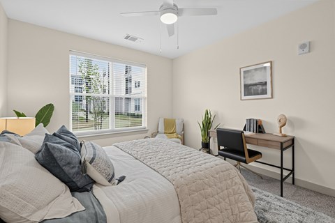 A bedroom with a large bed and a desk with a chair.