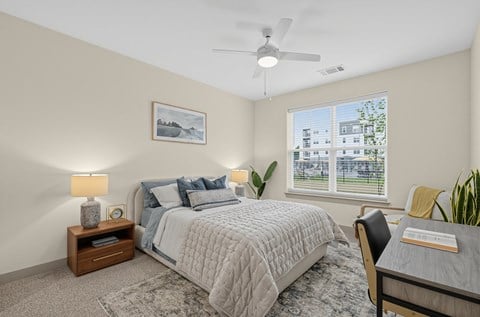 A bedroom with a bed, a chair, a desk, and a ceiling fan.