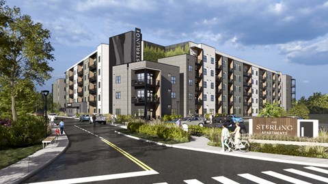 A Sterling apartment complex is shown with a person riding a bicycle on the street in front.