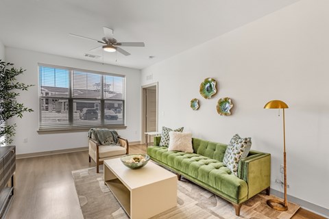 A living room with a green couch and a ceiling fan.