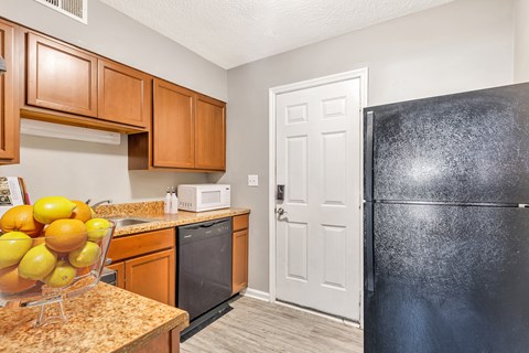a kitchen with a black refrigerator and a counter with fruit