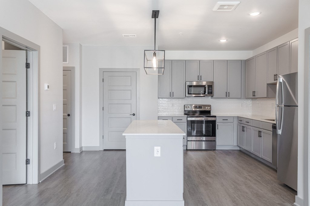 an empty kitchen with white cabinets and stainless steel appliances