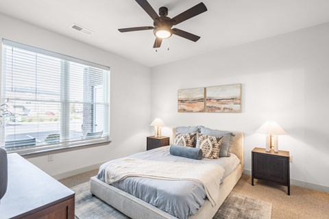 A bedroom with a bed, two lamps, and a painting on the wall.