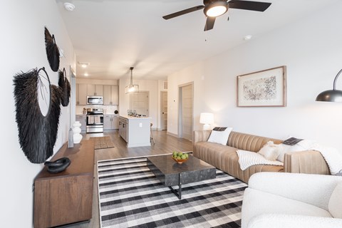 A modern living room with a striped rug and a ceiling fan.