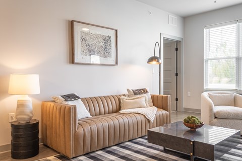 A living room with a tan couch, a coffee table, and a lamp.