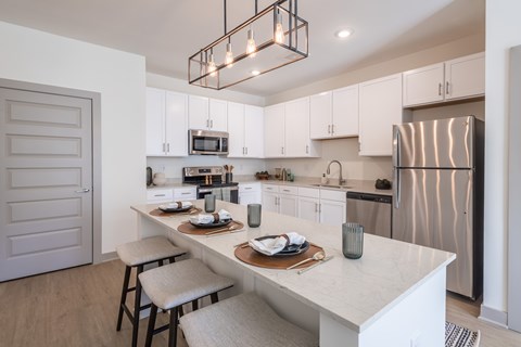 A modern kitchen with a white countertop and stainless steel appliances.