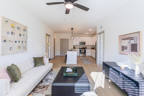 a living room with a couch and a coffee table in front of a kitchen