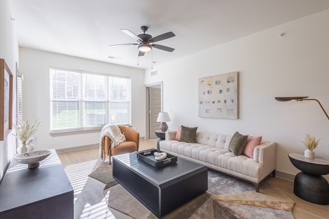 A living room with a couch, a chair, a coffee table, and a ceiling fan.