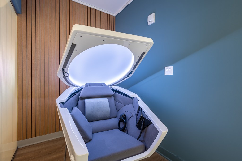 A modern, blue-toned room with a SomaDome meditation pod at The Warren Apartments, Jeffersonville, IN
