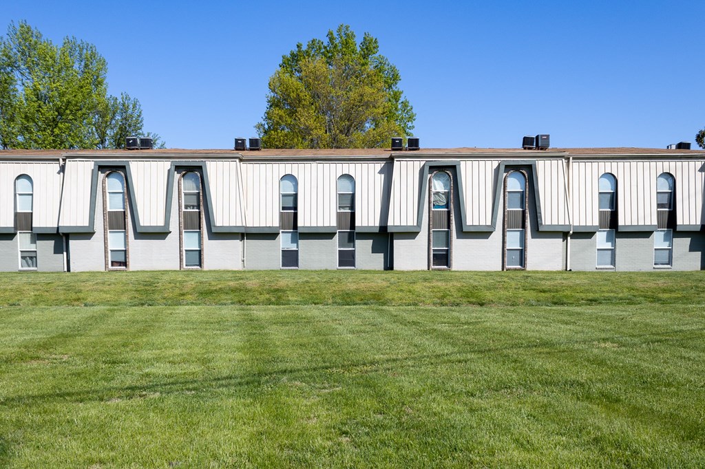 a building with many windows and a grassy area in front of it