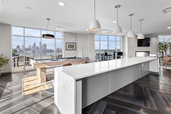 A modern kitchen with a long white island and a view of the city.