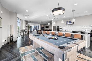 A pool table is in the middle of a kitchen and dining area.