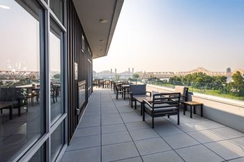 A patio with tables and chairs overlooking a bridge.