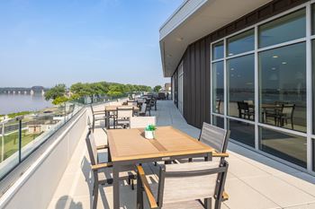 A table with chairs is on a balcony overlooking a body of water.