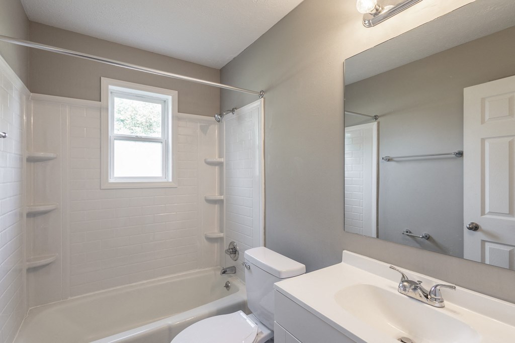 a bathroom with a white toilet next to a white sink and tub