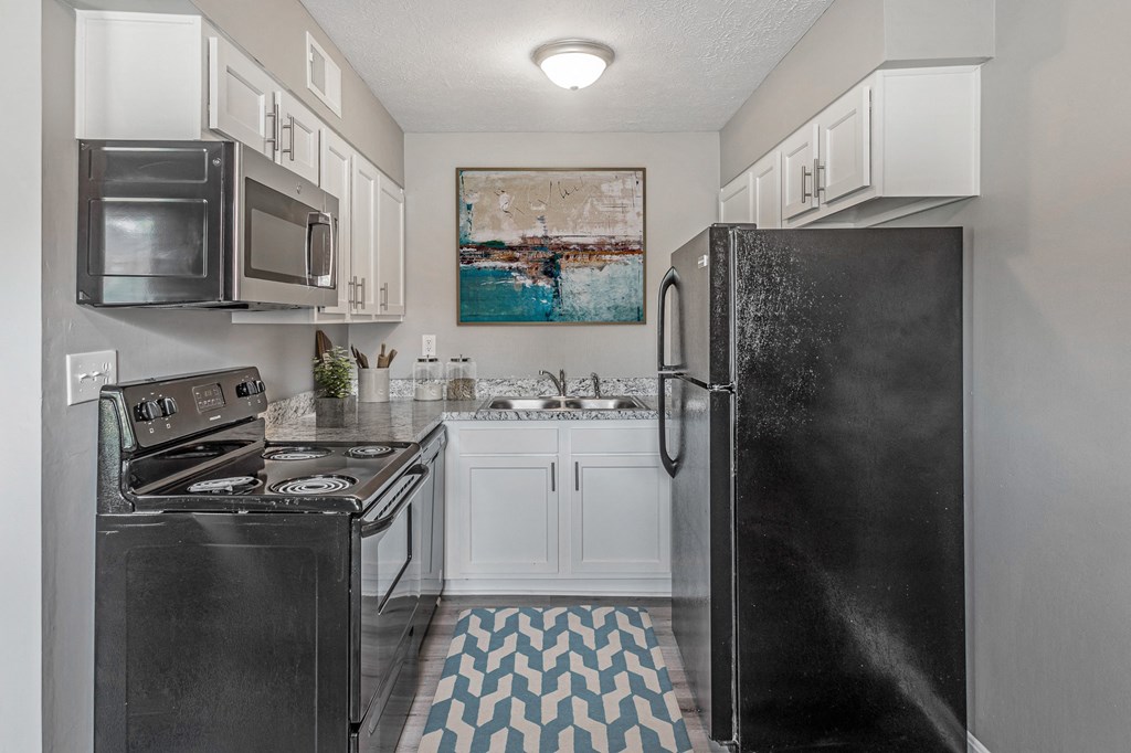 a kitchen with white cabinets and black appliances