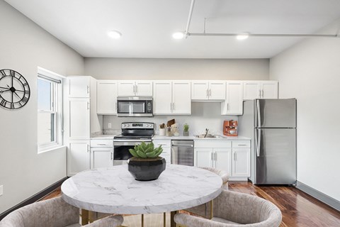 a white kitchen with stainless steel appliances and a marble table