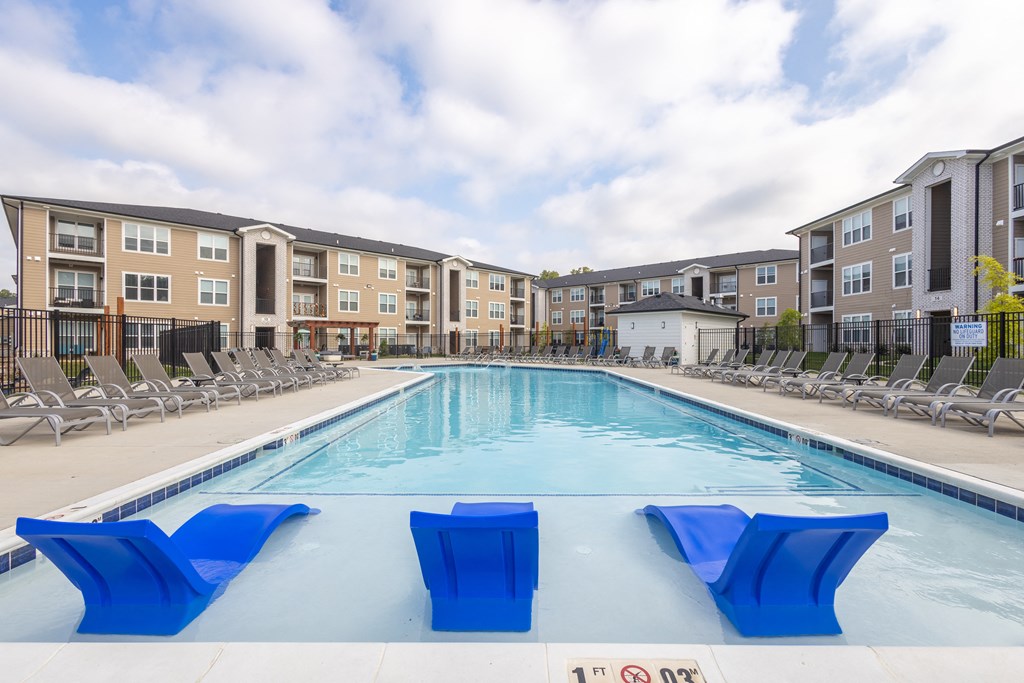 an outdoor pool with blue chairs and an apartment building at Arlington Farms, Greenwood Indiana