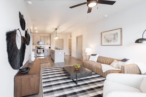 A modern living room with a striped rug and a ceiling fan.