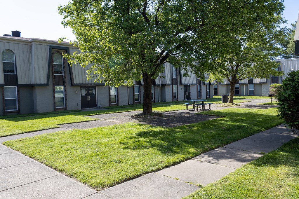 a courtyard with trees and a picnic table in front of a building