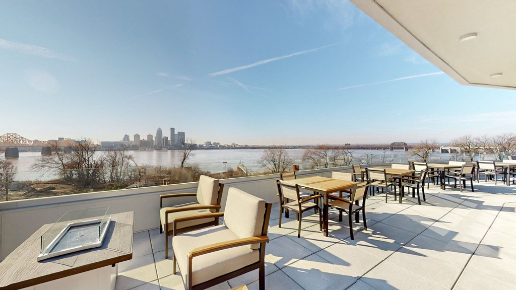 a patio with tables and chairs overlooking a river and a city at Current812, Clarksville