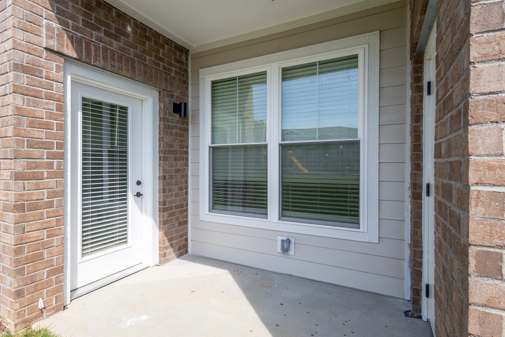 the front porch of a brick house with a white door and windows