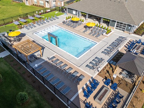A large outdoor swimming pool surrounded by sun loungers and umbrellas.