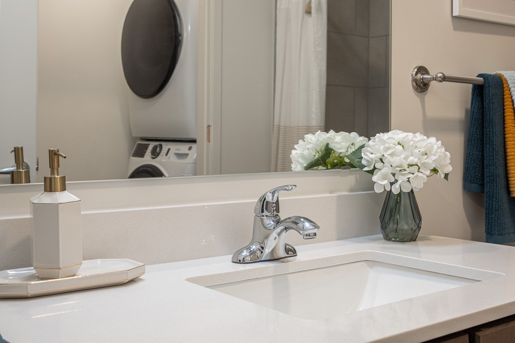 A white sink with a silver faucet and a vase of white flowers on the counter at Current812, Clarksville, Indiana
