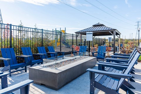 A gazebo is surrounded by blue chairs and a fire pit at The Warren Apartments, Jeffersonville, IN