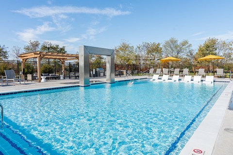 A large swimming pool with a blue tinted water and a white line around it at The Warren Apartments, Jeffersonville, IN