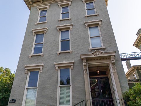 A tall building with a balcony and a doorway on the ground floor.