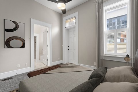 A living room with a grey couch and a ceiling fan.