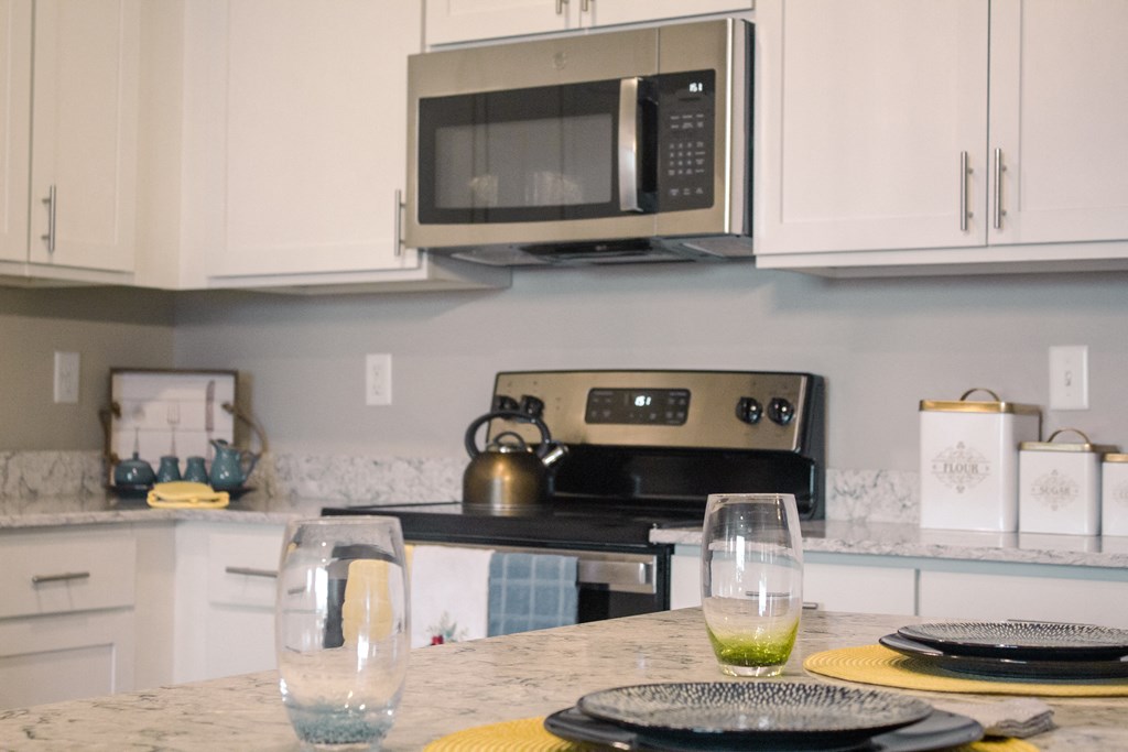 a kitchen with white cabinets and a counter top with glasses on it at Arlington Farms, Greenwood, IN 46143