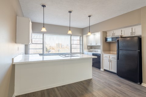 A kitchen with a black refrigerator and white cabinets at Lofts on Ormsby, Louisville, 40203