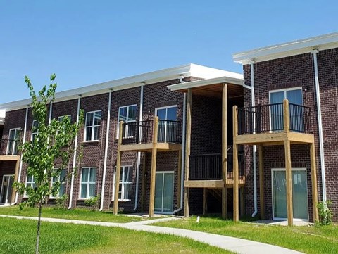 A row of red brick apartment buildings with balconies.