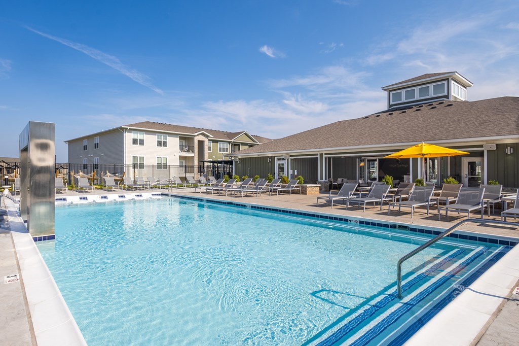 A swimming pool with a yellow umbrella and lounge chairs.