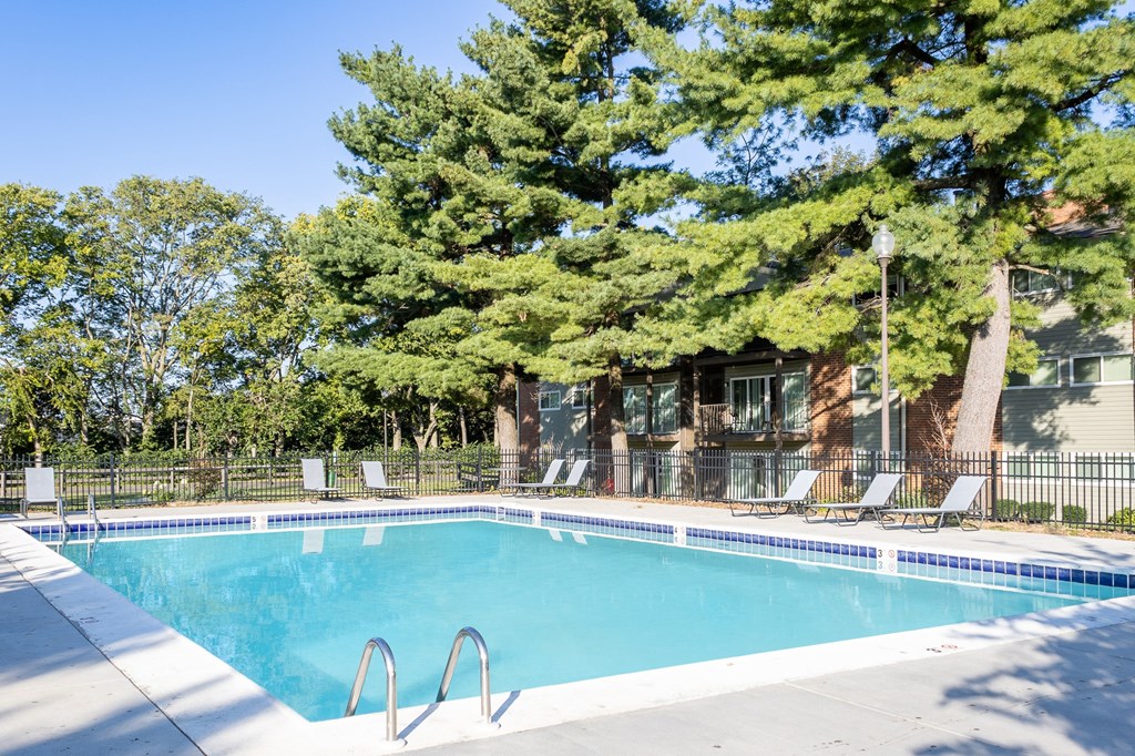 a swimming pool with chairs and a building in the background