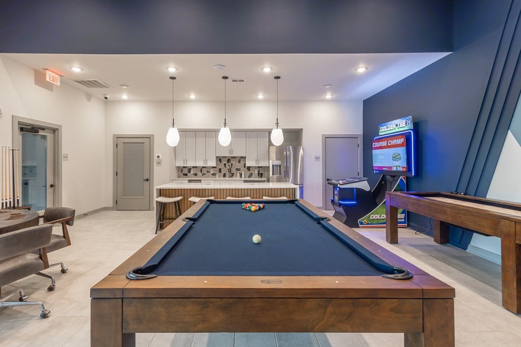 A pool table is in the middle of a room with a TV on the wall at The Warren Apartments, Jeffersonville, IN