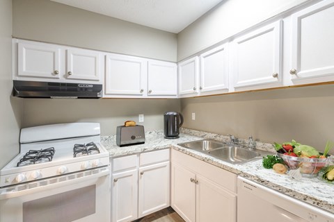 a kitchen with white cabinets and a stove and sink