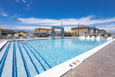 A large outdoor swimming pool with blue water and white lane markers.