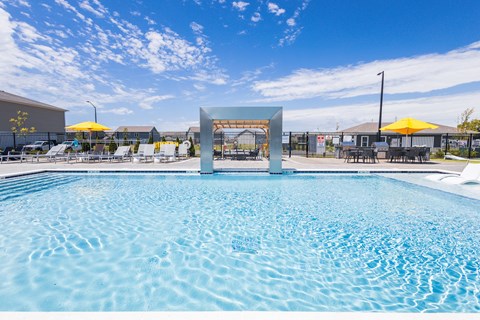 A large swimming pool with a blue tinted water and a white diving board.